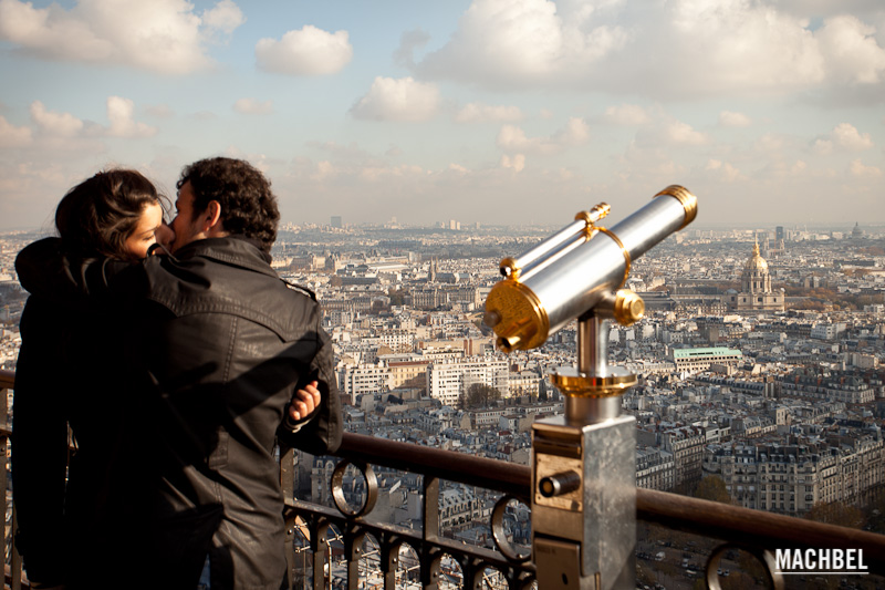 Pareja besándose al lado de un telescopio del mirador de la torre Eiffel, Paris, Francia