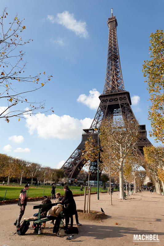 Grupo de personas sentadas en un banco frente a la torre Eiffel, Paris, Francia