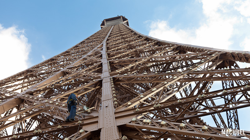 Técnico de mantenimiento amarrado a la estructura de la torre Eiffel, Paris, Francia