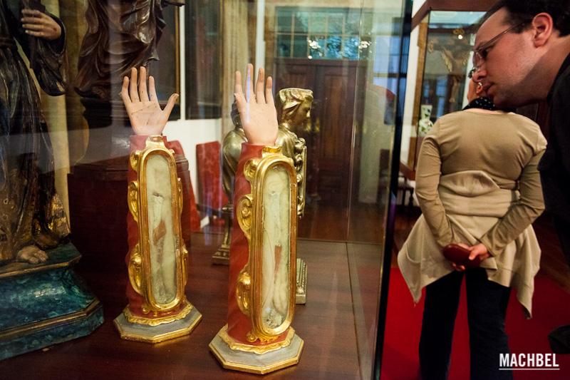 Un señor mira atentamente unas reliquias religiosas, unos brazos y manos disecadas