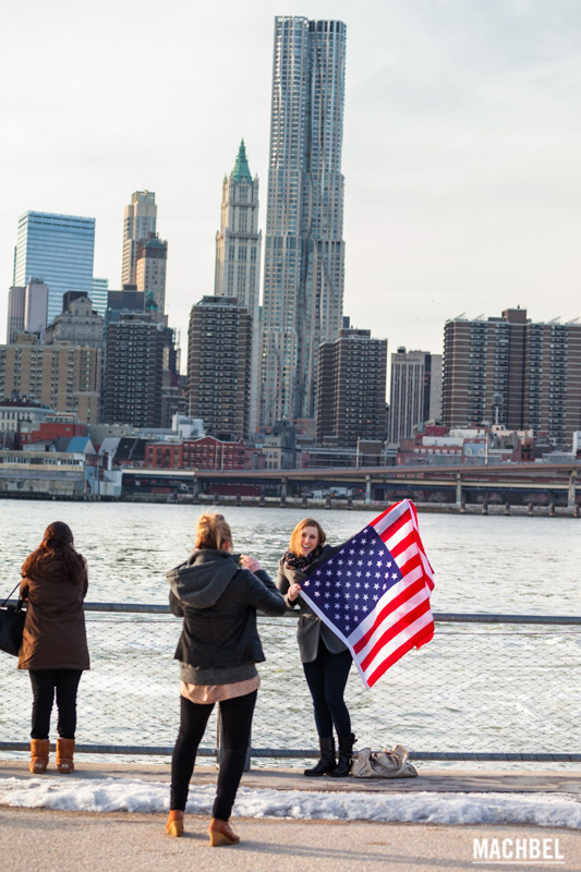 Chica con la bandera de Estados Unidos en frente del skyline de Nueva York